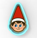 A cookie cutter in the shape of a smiling elf's face wearing a red hat.