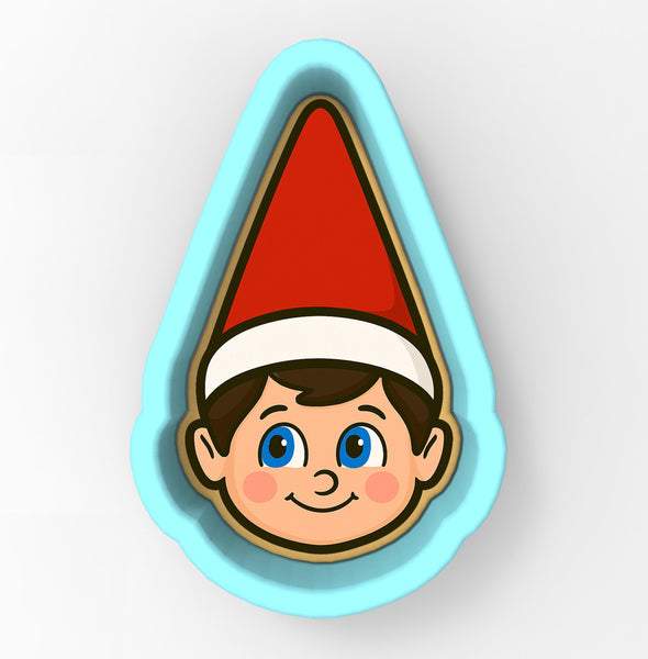 A cookie cutter in the shape of a smiling elf's face wearing a red hat.