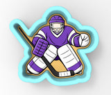 A cartoon illustration of a hockey goalie in a purple jersey and white pads, holding a hockey stick and ready to defend the goal.