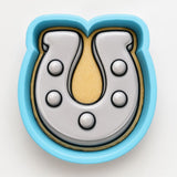 A blue cookie cutter shaped like a horseshoe, with a yellow interior.