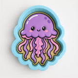 A blue cookie cutter shaped like a purple jellyfish with pink tentacles.