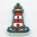 A cookie cutter shaped like a lighthouse, with a red and white striped body, a yellow light at the top, and a red door at the bottom.