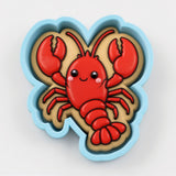 A cookie cutter shaped like a red lobster with a smiling face.