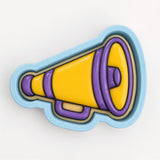 A 3D printed cookie cutter in the shape of a megaphone, with a yellow body and purple accents.