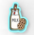 A cookie cutter shaped like a glass bottle with a straw, containing a cookie inside, and two chocolate chip cookies next to it.