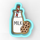 A cookie cutter shaped like a glass bottle with a straw, containing a cookie inside, and two chocolate chip cookies next to it.