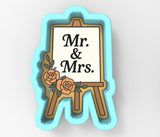 A 3D-rendered image of a blue easel with a white sign that reads "Mr. & Mrs."