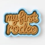 A blue cookie cutter shaped like the word "Rodeo" with the letters arranged in a playful, decorative manner.