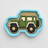 A green and beige toy car-shaped cookie cutter with a blue border.