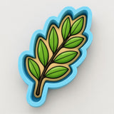 A blue cookie cutter shaped like a leaf with green leaves on it.