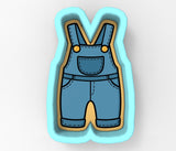 A cookie cutter in the shape of a letter 'V' with a pair of blue overalls depicted on it.