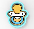 A baby pacifier cookie cutter in the shape of a smiling baby's face.