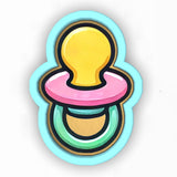 a pacifier with a yellow pacifier on top of it