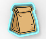 A cookie cutter in the shape of a brown paper bag.