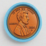 A copper-colored coin with a profile portrait of Abraham Lincoln, surrounded by a blue border.
