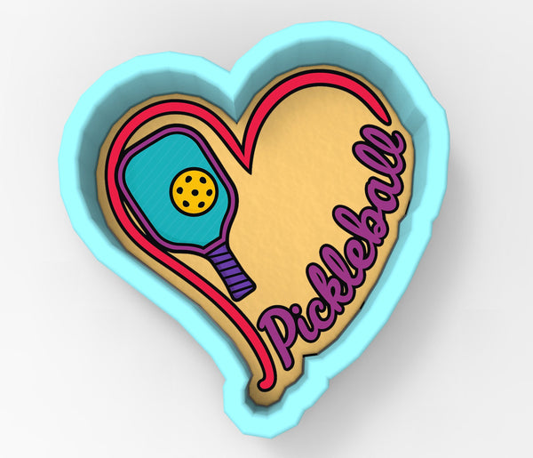 A heart-shaped cookie cutter with a pikachu-themed design, featuring a pikachu-shaped paddle and the word "Pickball" written on it.