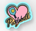 A heart-shaped cookie cutter with a paddleball symbol and the word "Pickleball" written on it.