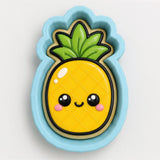 A cookie cutter in the shape of a pineapple with a smiling face and a leafy top.