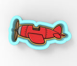 A red airplane cookie cutter with a propeller on top, designed for use in baking.