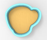 A blue-bordered, heart-shaped container filled with a yellow substance, possibly sand or clay.