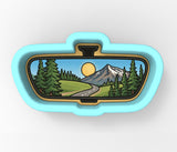 A mirror with a scenic landscape of mountains, trees, and a winding road visible through it.