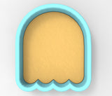 A blue cookie cutter shaped like a ghost with a yellow interior.
