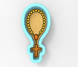 A blue-bordered cookie cutter shaped like a cross with a rosary around it.