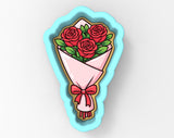 A cookie cutter in the shape of a bouquet of red roses, with a bow on the bottom.