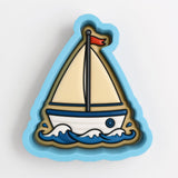 A cookie cutter shaped like a sailboat with a red flag on top, set against a blue background.