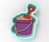 a cartoon of a bucket of sand with a shovel sticking out of it