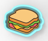 A blue cookie cutter shaped like a sandwich, with a slice of bread, lettuce, and cheese visible.