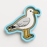 A cartoon seagull is depicted in a blue and yellow cutout shape against a white background.