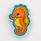 A cartoon-style seahorse with a vibrant orange body and yellow fins, set against a light blue background.