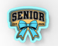 a blue ribbon with the word "SENIOR" written on it, along with the year "2026" below it.