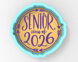 A cookie cutter-shaped sign with the text "SENIOR class of 2026" in purple and yellow colors.