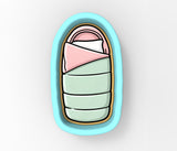 A cartoon illustration of a baby's crib with a pink blanket and a green blanket.
