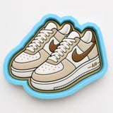 A pair of white and brown Nike Air Force 1 sneakers with the Nike Air logo visible.