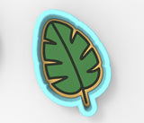 A green leaf-shaped cookie cutter with a blue outline.