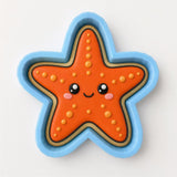 A cookie cutter in the shape of a smiling starfish with orange and blue colors.
