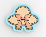 A cookie cutter in the shape of a hat with a bow on it.