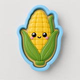 A cookie cutter shaped like a corn cob with a smiling face and green leaves.