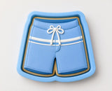 A blue cookie cutter shaped like a pair of blue swim shorts.