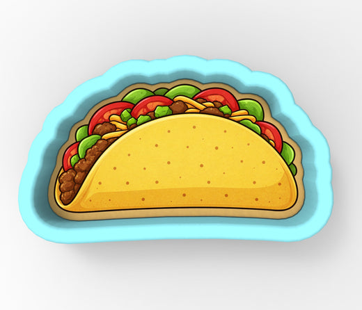 A blue cookie cutter shaped like a taco filled with various toppings.