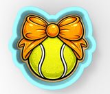 A tennis ball with a yellow and orange bow on it, set against a light blue background.