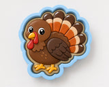 A cookie cutter in the shape of a turkey with a blue border.