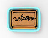 A welcome sign with the word "welcome" written on it, placed in a blue tray.