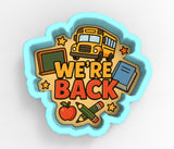 A cookie cutter-shaped design with the text "WE'RE BACK" surrounded by various school-related items such as a school bus, chalkboard, books, and pencils.