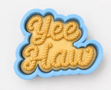 A cookie cutter shaped like the word "Yeehaw" made of frosting.