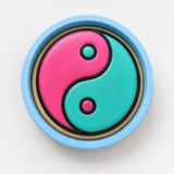 A blue bowl with a colorful design inside, featuring a pink and teal symbol.